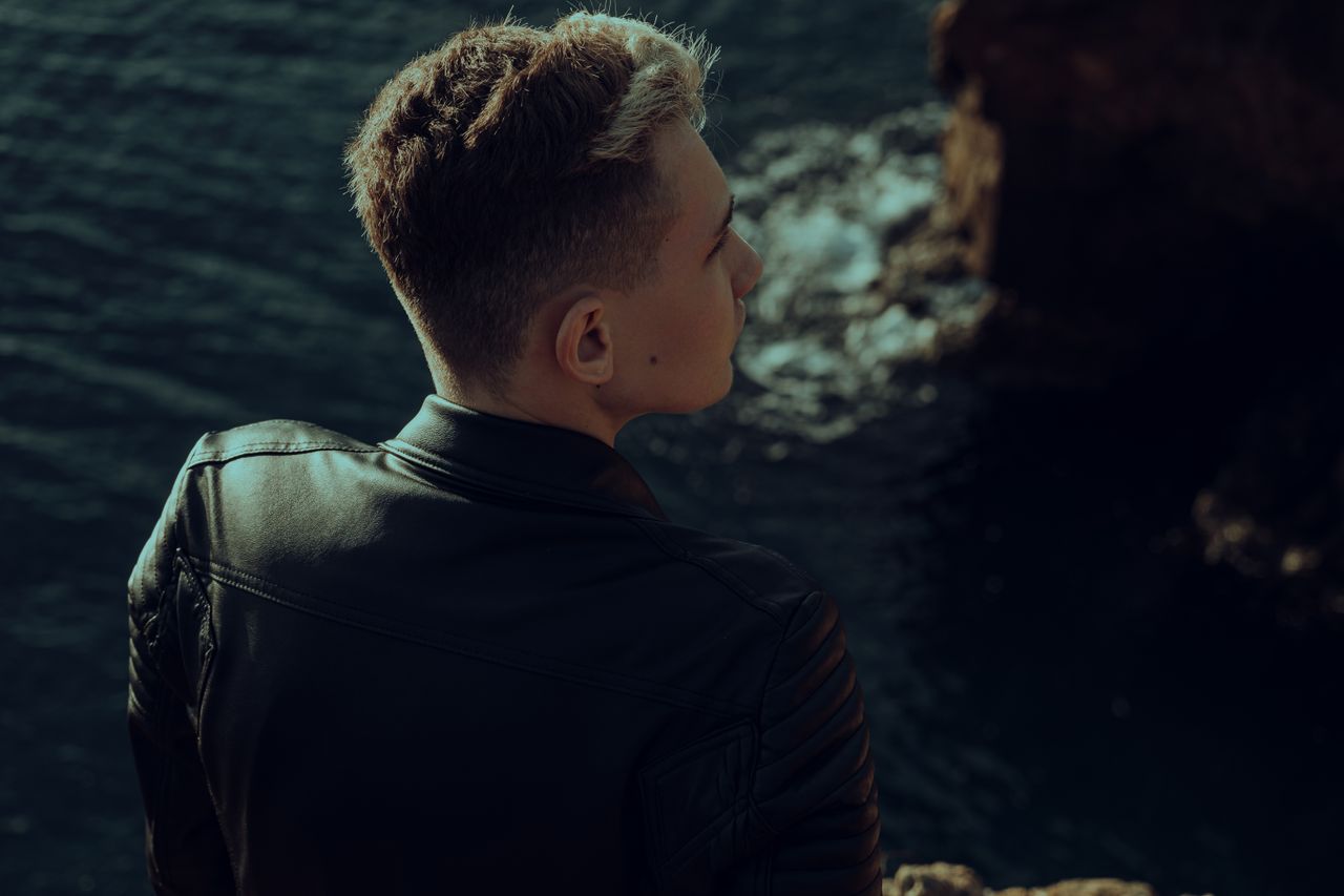 The Art of Drawing Readers In: Your attractive post title goes here Young man in leather jacket looking thoughtfully over the sea from a rocky edge.