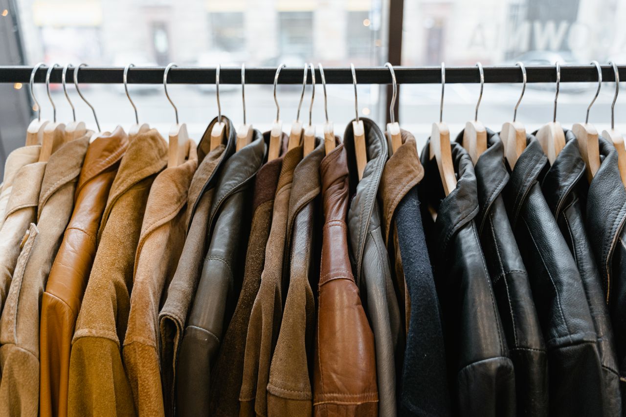 Home A collection of leather and suede jackets hanging on a clothes rack in a stylish boutique.